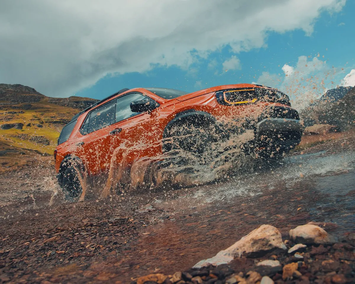 Side profile shot of the 2026 Honda Passport driving through small stream kicking up water.
